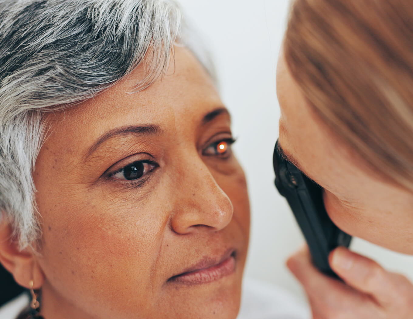 Clinician examining a patient’s eye with a handheld ophthalmoscope.